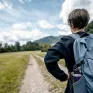 Jeune, de dos, avec un sac à dos face à une route de campagne